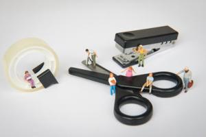 Miniaturfiguren vor Arbeitsmaterial - Schere und Klebefilm