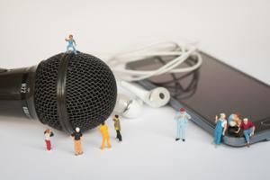 Mikrofon und Smartphone mit Miniaturfiguren