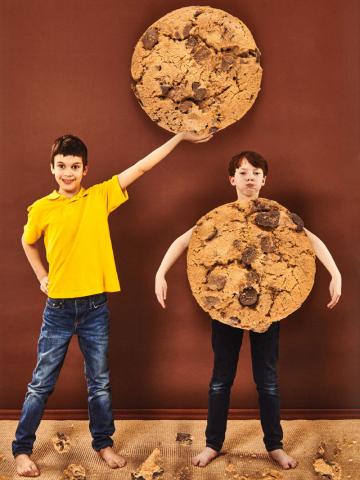  Zwei Kinder spielen mit Riesenkeksen