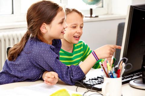 Mädchen und Junge schauen auf einen Computermonitor 