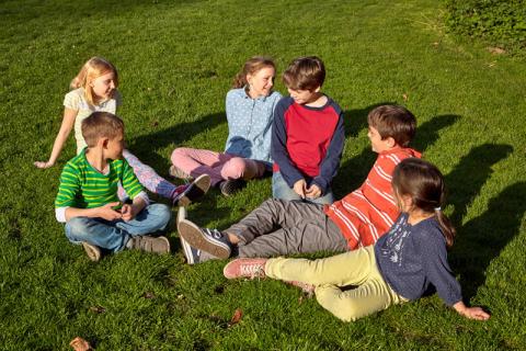 Sechs Kinder sitzen auf der Wiese