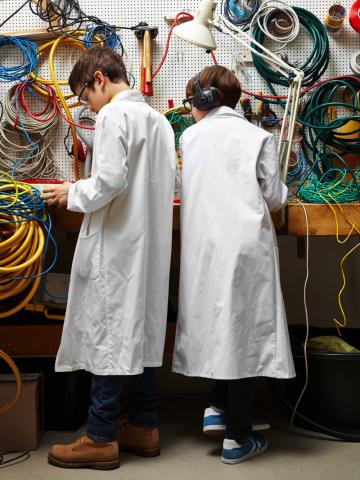 Zwei junge Erfinder in weißen Kitteln stehen im Kabellabor