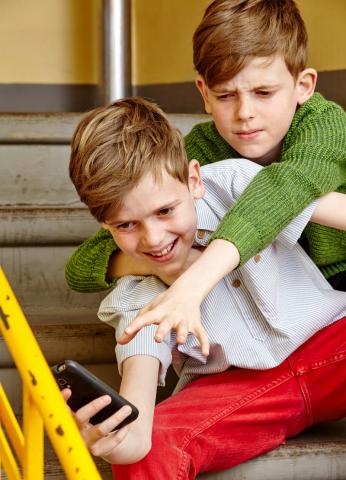 Zwei Jungen streiten sich um ein Smartphone