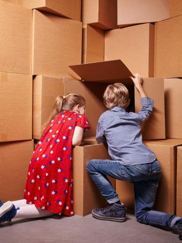 Ein Mädchen und ein Junge schauen in einen von vielen Kartons