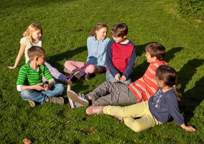 Sechs Kinder sitzen auf der Wiese