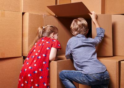 Ein Mädchen und ein Junge schauen in einen von vielen Kartons