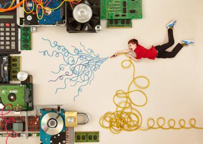 Ein Junge löscht mit einem Kabelschlauch verschiedene Computer und Geräte