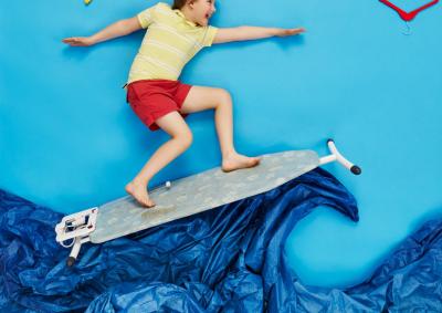 Ein kind surft fröhlich auf Papierwellen und Bügelbrett